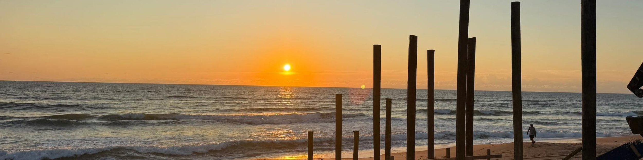 Sunrise over piling posts and waterfront dock